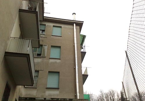 Comignolo in rame con cappello antipioggia su un tetto a Bologna